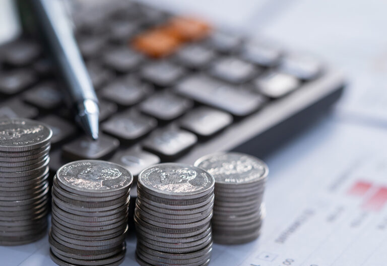 Stack of coins next to a keypad calculator