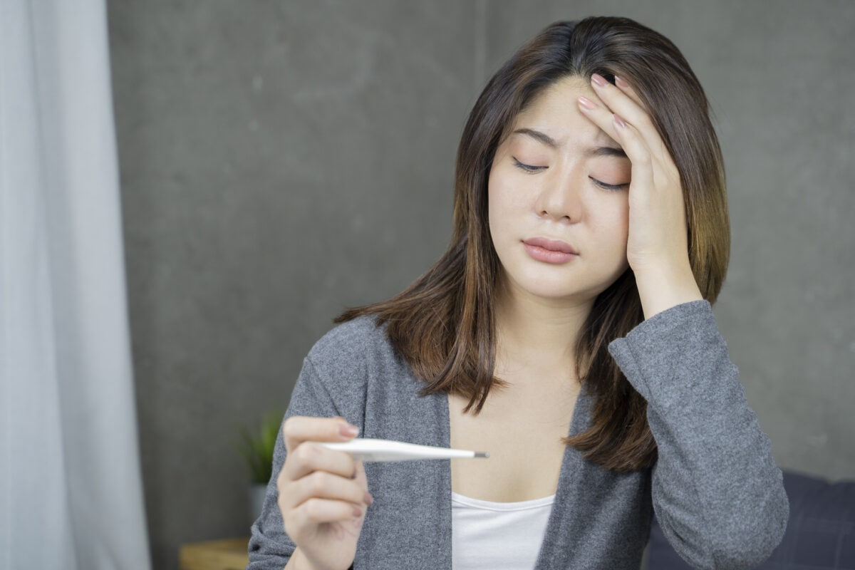 Feeling illness. Closeup of beautiful unhealthy girl looking at thermometer. Healthcare concept.