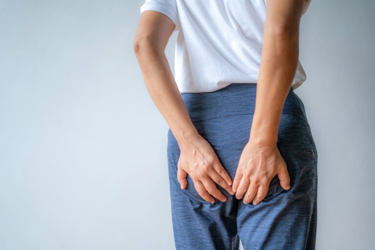 Woman hand holding her bottom because having Abdominal pain and Hemorrhoids, Health care concept.