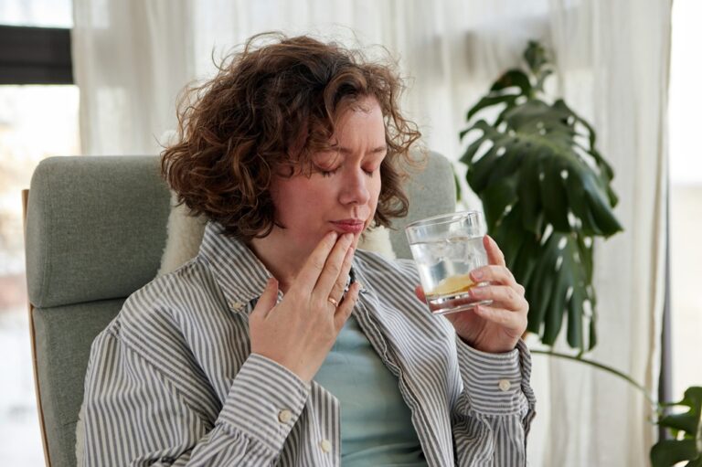 Woman's reaction to a sip of cold water with lemon while sitting in a chair at home