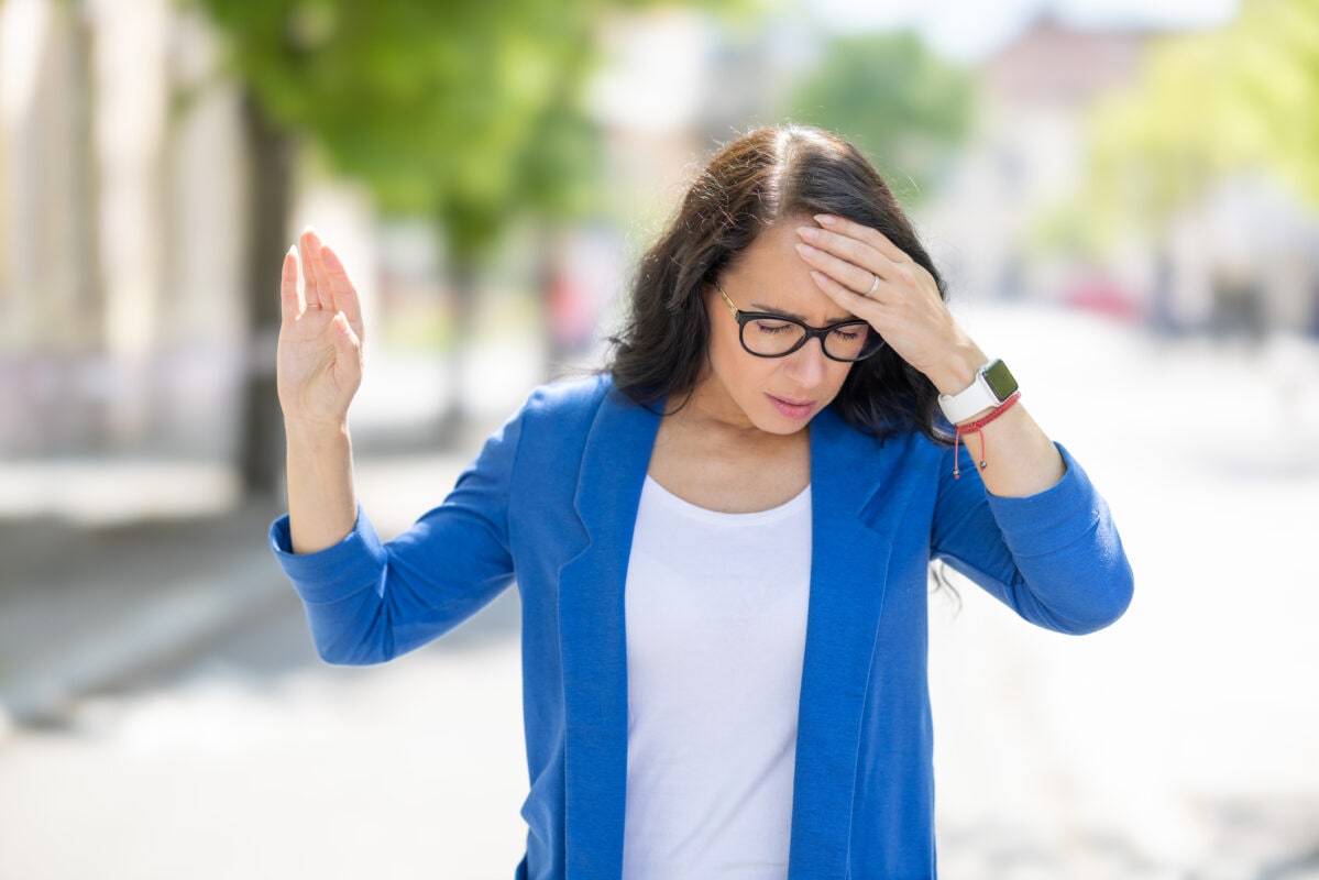 The young business woman suddenly feels dizzy and struggles to keep her balance. Disoriented woman suffering from vertigo.