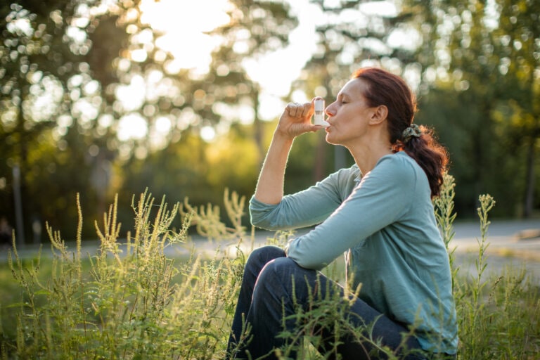 Woman sitting outdoors and suffering from pollen allergy